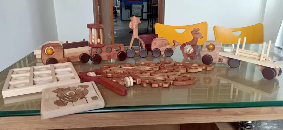Cam masa üzerinde ahşap tekerlekli arabalar, hayvan figürleri ve yapboz parçaları