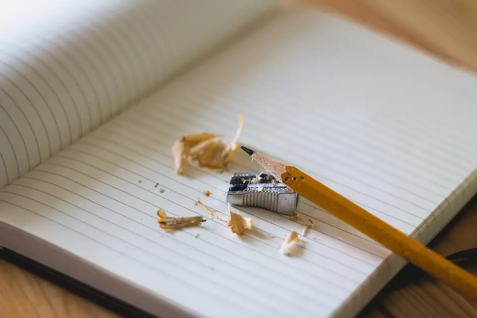 Çizgili bir defter üzerinde kalemtıraş, kurşun kalem ve kalem talaşları