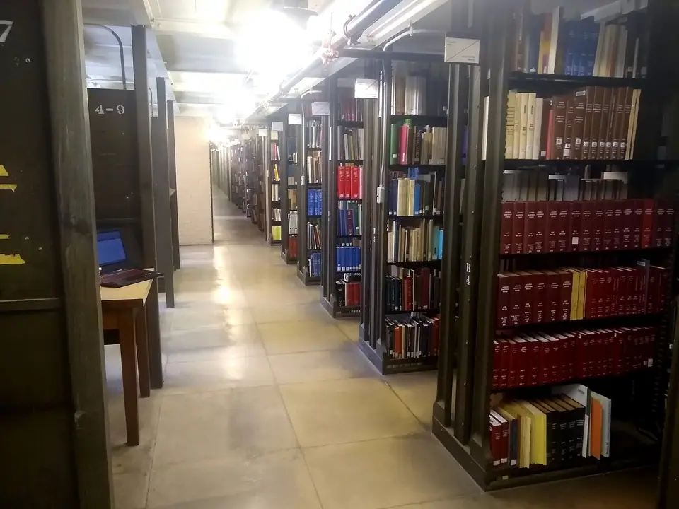 Bir kütüphanede uzun koridor boyunca sıralanmış kitap rafları